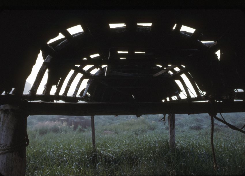 The underside of an old umiak resting on a rack.